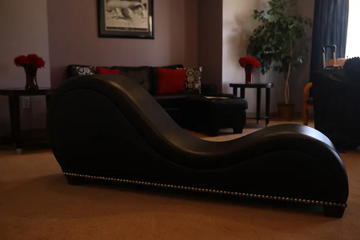 Black leather Tantra chair in an upscale room with decorative pillows, flowers, and warm ambient lighting